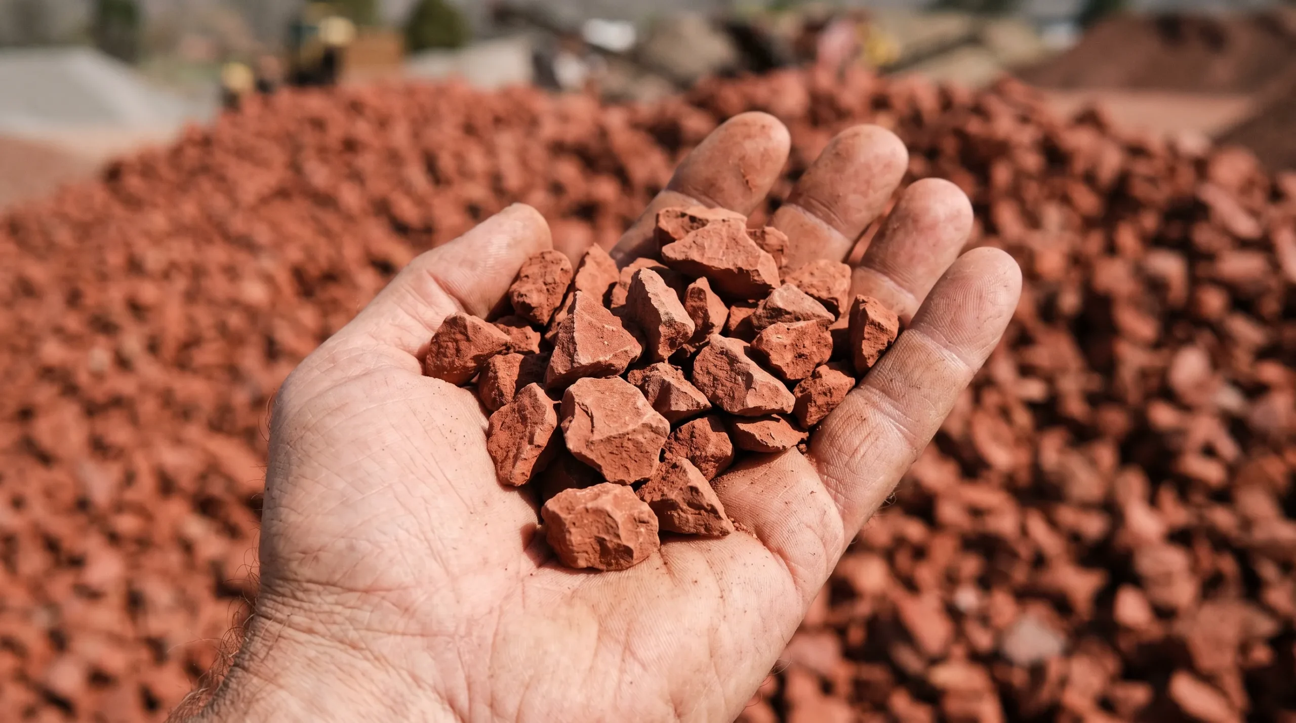 Rich, deep red crushed Napa stone chips held in a hand showing texture and consistent size grading.